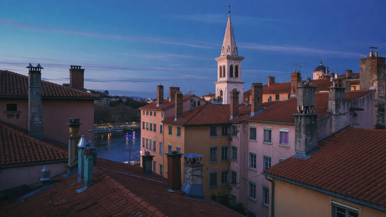 Toits de tuiles lyonnais à l’heure bleue, clocher et Saône en contrebas.